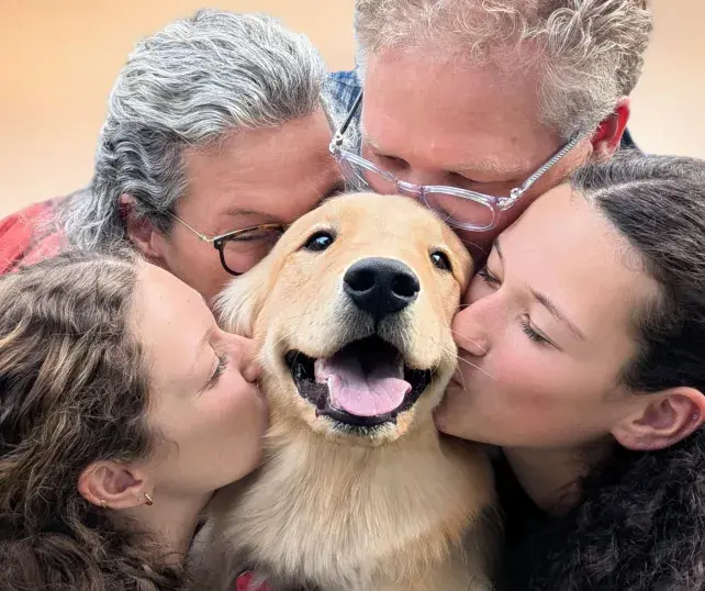 Four volunteers giving a dog some kisses.
